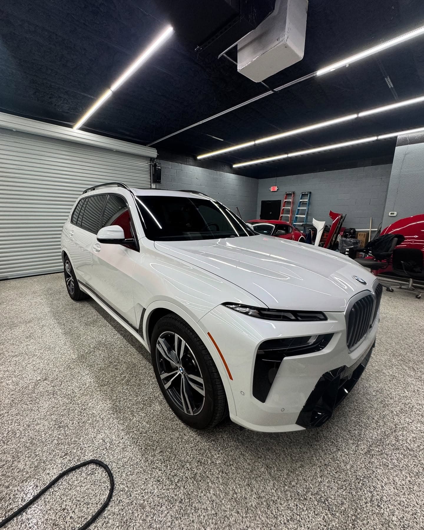 White BMW X7 with freshly tinted windows in the install bay