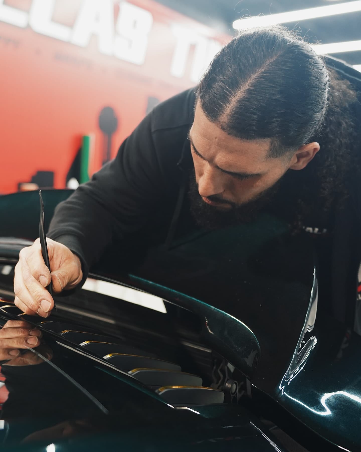 Installer finishing a vinyl wrap on a Porsche in the Dallas Tint Shop bay